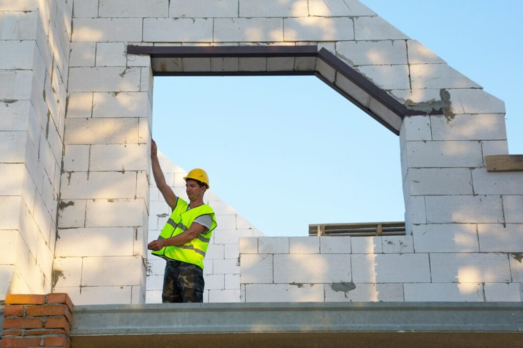 Construction worker at construction site measures the length of the window opening and the wall
